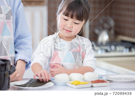 ファミリー おにぎりに海苔を巻く女の子の写真素材