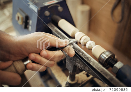Work at the lathe. Master's hands with a chisel close-up. Processing of a wooden part. Employment and labor. 72099686