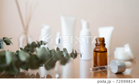Serum or essential oil with organic herbal extract. Brown glass vial with dropper and skincare bottles on wooden table. Natural cosmetic, spa, beauty product and aromatherapy concept. 72099814