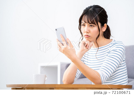 リビングでくつろぎながらスマホを操作する女性。 リビングでくつろぎながらスマホを操作する女性。 72100671