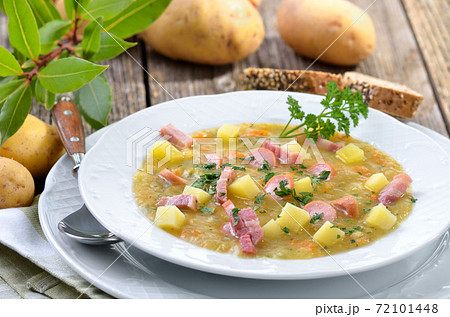 Freshly made potato soup with bacon strips and sausage wheels, served with bread 72101448