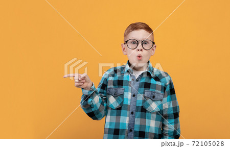 Amazed kid showing shocking advertisement, aiming at copy space Amazed kid showing shocking advertisement, aiming at copy space 72105028