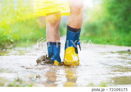 child's feet in a rubber boot in a puddle 72106175