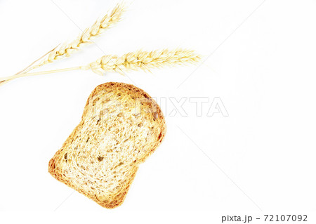 Crusty bread toast slice next to two ears of wheat on white background Crusty bread toast slice next to two ears of wheat on white background 72107092