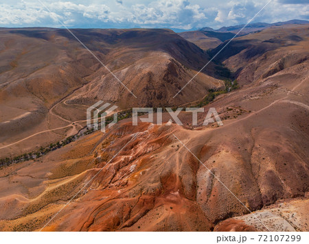 Aerial shot of the textured yellow nad red mountains resembling the surface of Mars 72107299