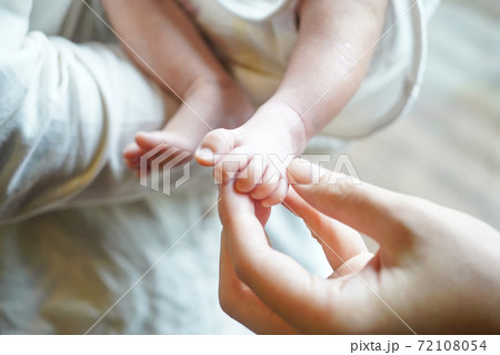 赤ちゃんの足を持つお母さんの手 赤ちゃんの足を持つお母さんの手 72108054