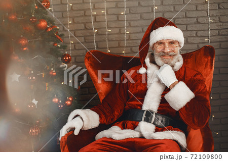 Man in santa claus costume sitting on a chair Man in santa claus costume sitting on a chair 72109800