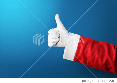 Santa Claus hand showing thumbs up gesture with a colored background Santa Claus hand showing thumbs up gesture with a colored background 72111356