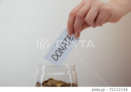 Coins in a glass bank and female's hand close-up. Donation concept 72112148