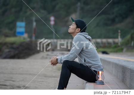 二地域暮らしで週末、早朝に浜でゆっくりすごす男性 72117947