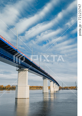 Sunset river gateway bridge blue sky and clouds. Autumn River bridge view. Cargo ships loading in cargo terminal on background Sunset river gateway bridge blue sky and clouds. Autumn River bridge view. Cargo ships loading in cargo terminal on background 72123747