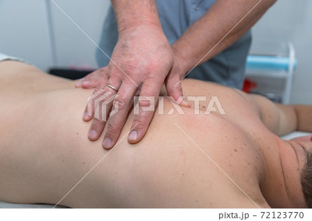 Masseur gives therapeutic massage to man. Male hands do massage of back to patient man. Male patient having massage in clinic. Man relaxing on massage table Masseur gives therapeutic massage to man. Male hands do massage of back to patient man. Male patient having massage in clinic. Man relaxing on massage table 72123770