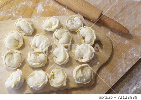 Closeup on semi-finished pelmeni dumplings on the wooden board. 72123839