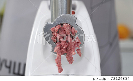 Filling comes out through raw meat grinder sieve. Grinder close up. Pile of chopped meat. Electric mincer machine with fresh chopped meat. Preparation of minced beef with an electric meat grinder. Filling comes out through raw meat grinder sieve. Grinder close up. Pile of chopped meat. Electric mincer machine with fresh chopped meat. Preparation of minced beef with an electric meat grinder. 72124354