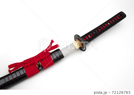Japanese sword with red cord steel fitting and shiny black scabbard on white background. Selective focus. Japanese sword with red cord steel fitting and shiny black scabbard on white background. Selective focus. 72126765