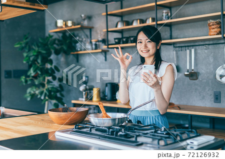 スマホを見ながら料理をする女性 スマホを見ながら料理をする女性 72126932