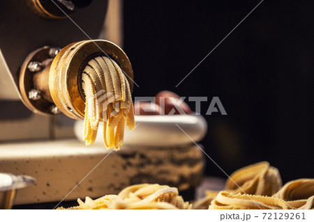 Fresh fettuccine pasta leaving pasta making machine Fresh fettuccine pasta leaving pasta making machine 72129261