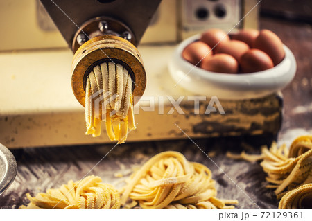 End of pasta making process with fresh fettuccine leaving the pasta maker End of pasta making process with fresh fettuccine leaving the pasta maker 72129361