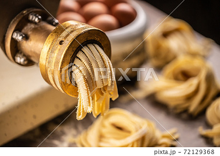 Fresh fettuccine pasta getting out of the pasta making machine Fresh fettuccine pasta getting out of the pasta making machine 72129368