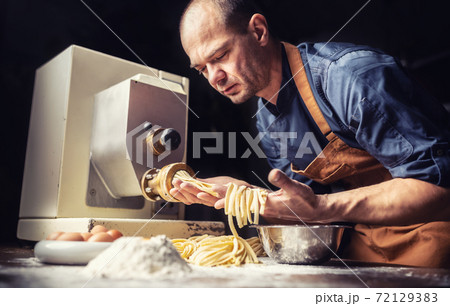 Pastaiolo chef making stripes of fresh fettuccine pasta dough Pastaiolo chef making stripes of fresh fettuccine pasta dough 72129383