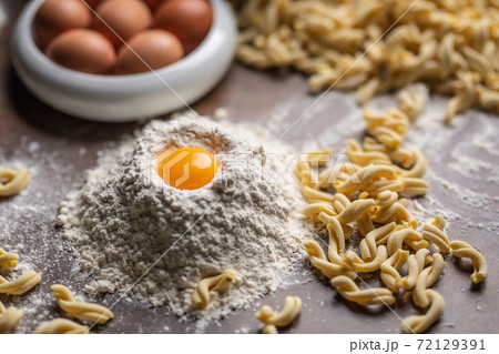 Pile of flour with an egg yolk and fresh pasta on a cooking desk 72129391