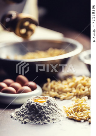 Eggs, flour and freshly made pasta out of the pasta maker on a dark background Eggs, flour and freshly made pasta out of the pasta maker on a dark background 72129396