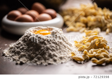Fresh pasta recipe with flour, egg yolk and a twisted shaped pasta pieces Fresh pasta recipe with flour, egg yolk and a twisted shaped pasta pieces 72129398