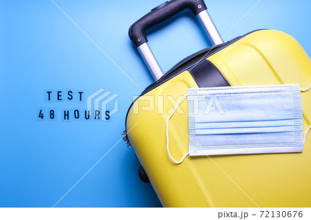 Luggage bag and mask on a blue background. Word test for covid 48 hours. Travel only with a covid test. 72130676