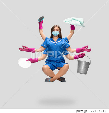 Female housemaid in pink gloves and blue uniform multitask like shiva isolated on gray background. Safety during COVID-19 Female housemaid in pink gloves and blue uniform multitask like shiva isolated on gray background. Safety during COVID-19 72134210