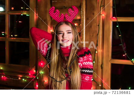 Beautiful girl with festive lights wearing red sweater 72136681