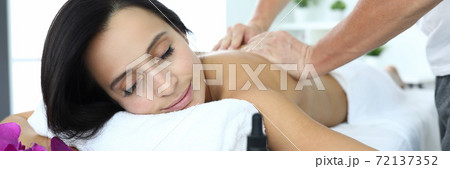Woman lies on massage table she is being massaged. 72137352
