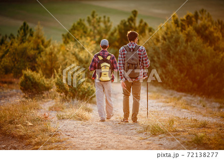 two men hikers enjoy a walk in nature, sunset time in summer two men hikers enjoy a walk in nature, sunset time in summer 72138277