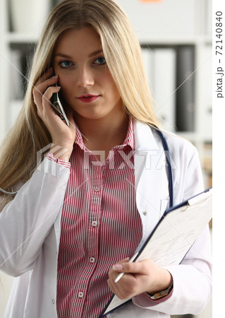 Beautiful female blond doctor talking on phone 72140840