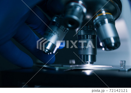 Sample slide and microscope with metal lens at laboratory. 72142121