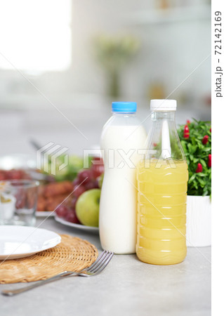 Close up of bottles of milk and orange juice served with Latin American breakfast on the table in modern kitchen interior 72142169