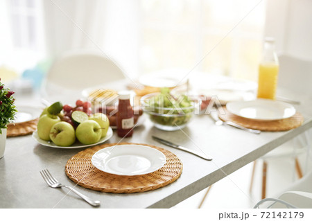 Start of the day. Close up of empty white plate and Latin style breakfast on the table. Modern bright white kitchen interior with wooden and white details 72142179