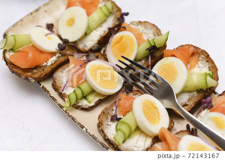 bruschetta with cheese, cucumber, salmon and boiled egg on a plate, 72143167