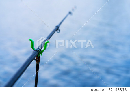 Fishing rod with a bell on the background of the river. Fishing hobby 72143358