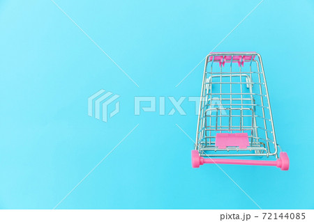 Small supermarket grocery push cart for shopping toy with wheels isolated on blue pastel colorful trendy background Copy space. Sale buy mall market shop consumer concept. 72144085