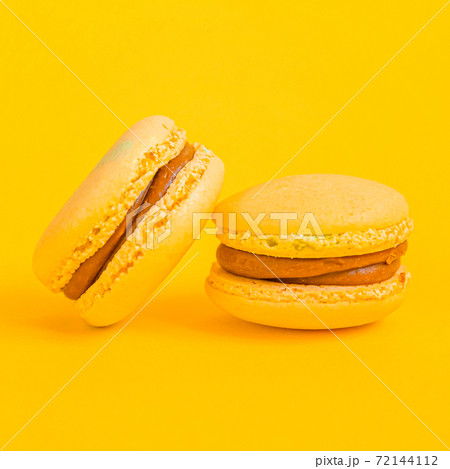 Sweet almond colorful yellow macaron or macaroon dessert cake isolated on trendy yellow modern fashion background. French sweet cookie. Minimal food bakery concept Copy space 72144112