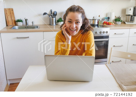 Mobile Office at home. Young woman sitting in kitchen at home working using on laptop computer. Lifestyle girl studying or working indoors. Freelance business quarantine concept. 72144192