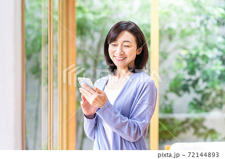 リビングでスマホを操作するミドル女性 72144893
