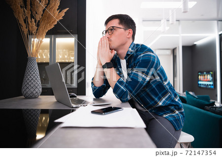 Portrait of a thoughtful young businessman working remotely from home using laptop 72147354