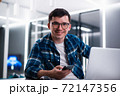 Portrait of handsome young man working remotely at home and smiling happily at camera 72147356