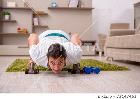 Young man doing sport exercises at home 72147463