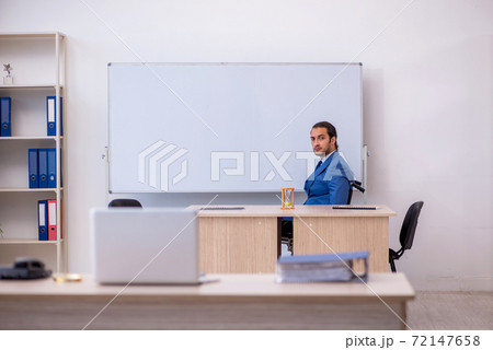 Young male employee in wheel-chair working in the office Young male employee in wheel-chair working in the office 72147658