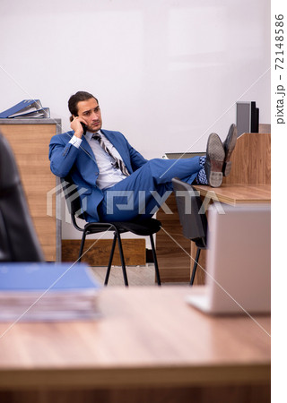 Young male employee sitting at workplace 72148586