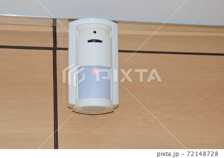 Motion sensor of the security alarm system. A white volume sensor hangs on the wall in a room or Motion sensor of the security alarm system. A white volume sensor hangs on the wall in a room or 72148728