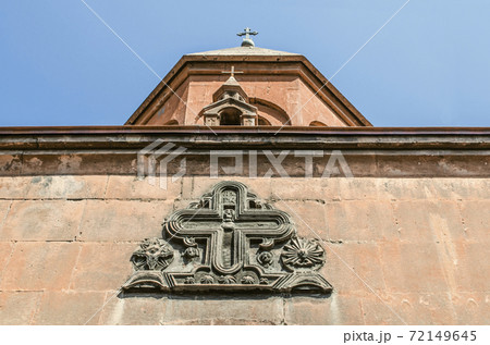 Figured cross with the faces of saints over the entrance to the "Zoravar" Church of the most Holy Virgin with a miniature Church on the roof in Yerevan Figured cross with the faces of saints over the entrance to the "Zoravar" Church of the most Holy Virgin with a miniature Church on the roof in Yerevan 72149645