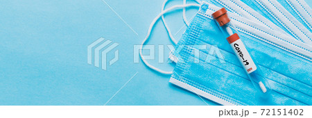 One single glass test tube containing a Corona virus test swab sitting on top of some blue surgical masks One single glass test tube containing a Corona virus test swab sitting on top of some blue surgical masks 72151402